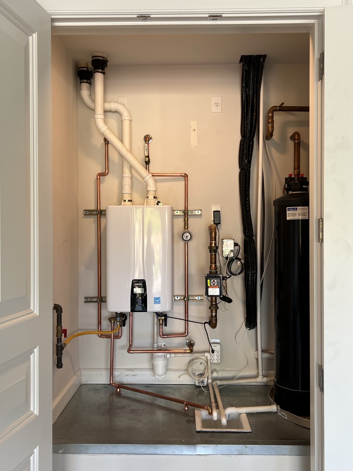 Wall-mounted tankless water heater with clean new copper piping after the hybrid to tankless conversion